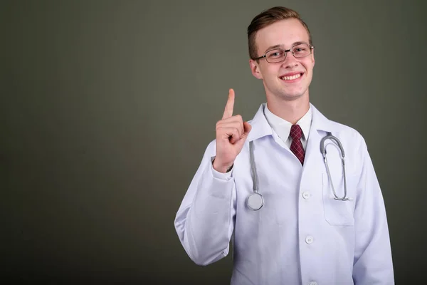 Fiatal jóképű férfi orvos ellen színes háttér — Stock Fotó