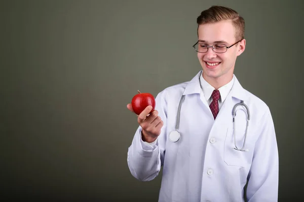 Молодой красивый мужчина врач на цветном фоне — стоковое фото
