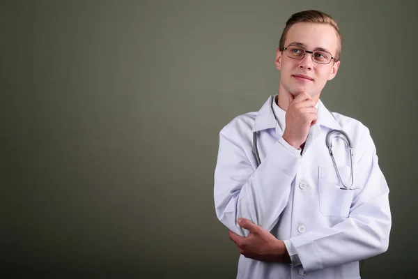 Fiatal jóképű férfi orvos ellen színes háttér — Stock Fotó