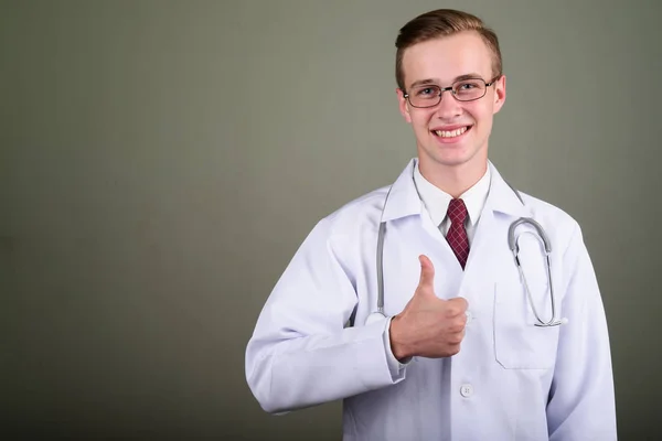 Jovem bonito homem médico contra fundo colorido — Fotografia de Stock