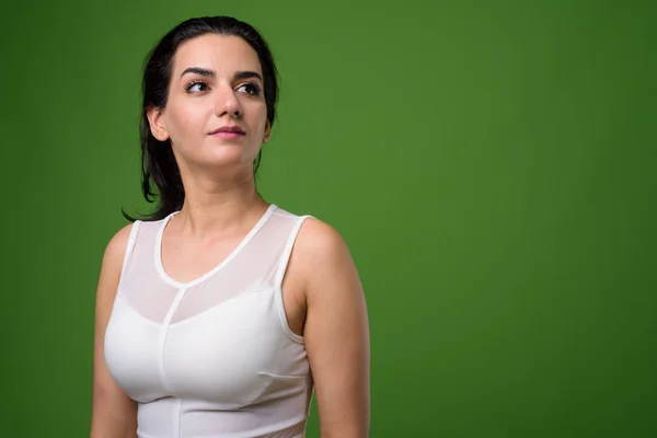 Portrait of beautiful Iranian woman against green background