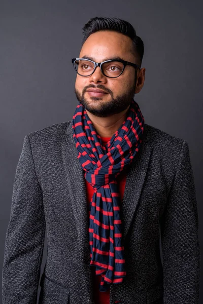 Jonge bebaarde Indiase zakenman tegen grijze achtergrond — Stockfoto
