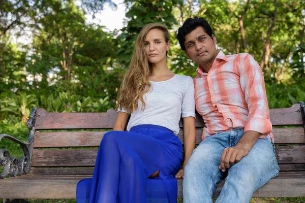 Πολυ εθνοτικών ζευγάρι κάθεται στο ξύλινο πάγκο στην αγάπη με την ειρηνική — Φωτογραφία Αρχείου