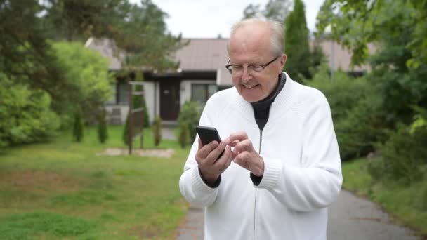 Heureux senior homme souriant tout en utilisant téléphone à la maison à l'extérieur — Video