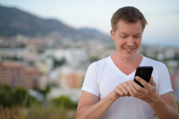 Νέοι ευτυχισμένη τουριστικά άνδρα χαμογελώντας ενώ χρησιμοποιώντας τηλέφωνο στη φύση — Φωτογραφία Αρχείου