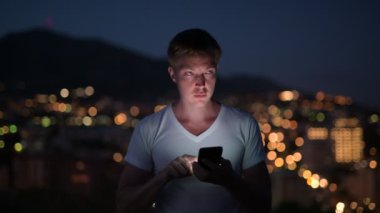 Geceleri ışıklar görünümünü karşı telefon kullanan genç mutlu turist adam