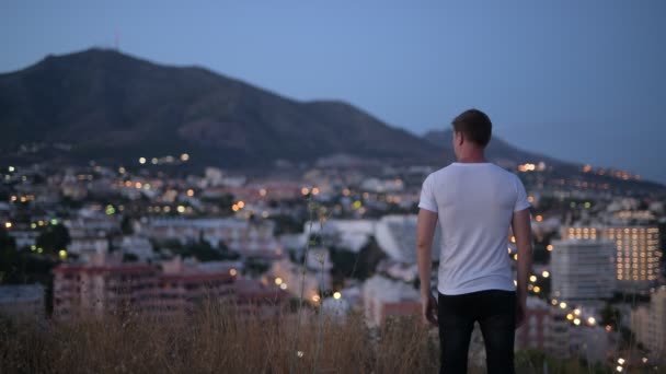 Bakifrån av ung turist Man med armarna upp på toppen av kullen på natten — Stockvideo