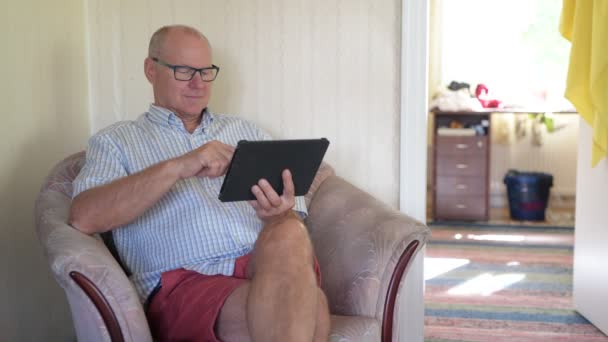Счастливый пожилой человек с помощью цифровых технологий в гостиной — стоковое видео