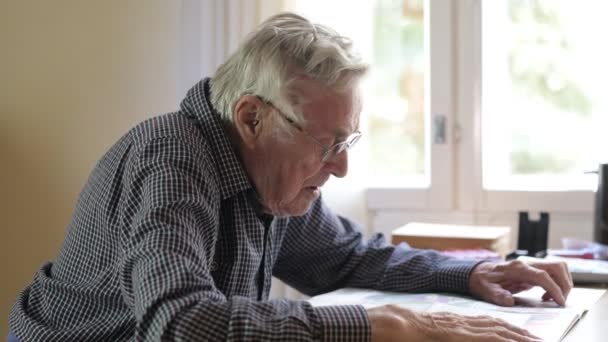 Senior Man läsa tidningen genom fönstret hemma — Stockvideo