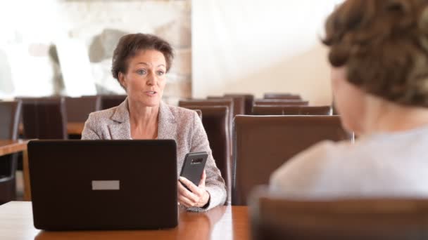 Mujer de negocios madura feliz usando la tecnología mientras que habla con la mujer mayor — Vídeo de stock