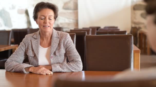 Mujer de negocios madura estresada hablando con una mujer mayor en la cafetería — Vídeos de Stock