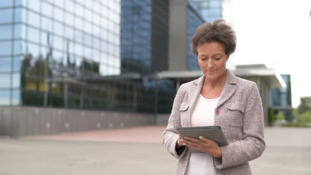 Heureuse femme d'affaires mature pensant tout en utilisant la tablette numérique à l'extérieur — Video