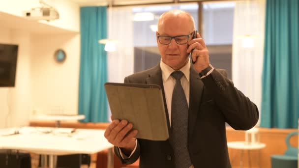 Hombre de negocios senior feliz hablando por teléfono mientras usa la tableta digital en el trabajo — Vídeos de Stock