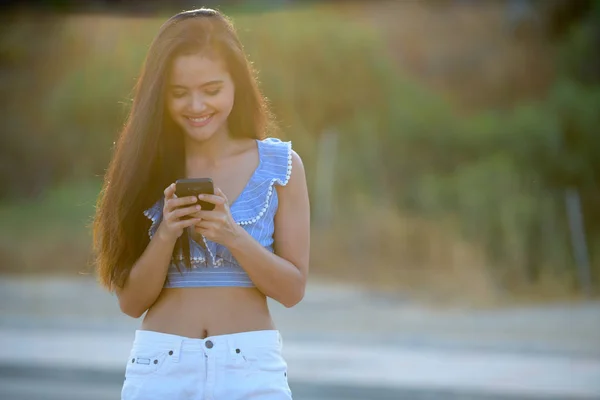 Giovane felice asiatico turista donna sorridente mentre usando telefono — Foto Stock