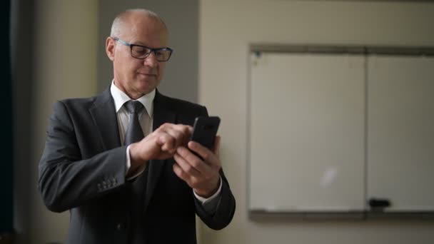Gelukkig Senior zakenman denken tijdens het gebruik van de telefoon bij het raam op het werk — Stockvideo