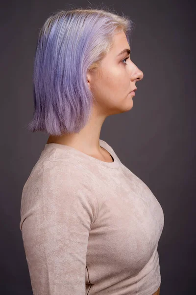 Junge schöne Rebellin mit buntem Haar gegen grauen Rücken — Stockfoto