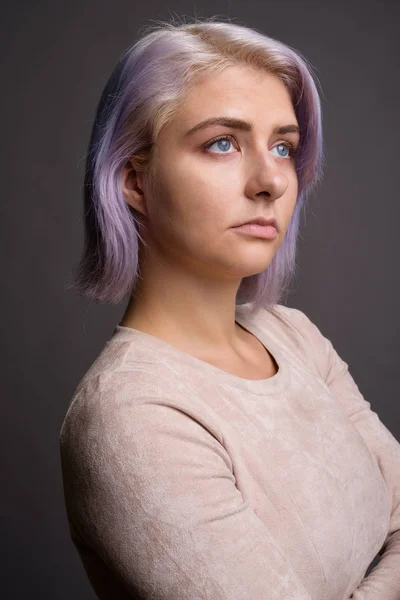 Jovem bela mulher rebelde com cabelo colorido contra costas cinza — Fotografia de Stock