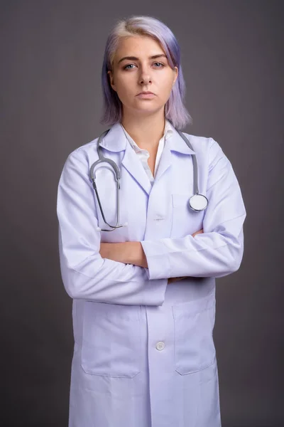 Young beautiful woman doctor with short colorful hair against gr — Stock Photo, Image