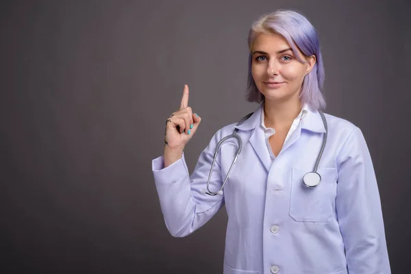 Mooie jongedame arts met kort kleurrijke haar tegen gr — Stockfoto