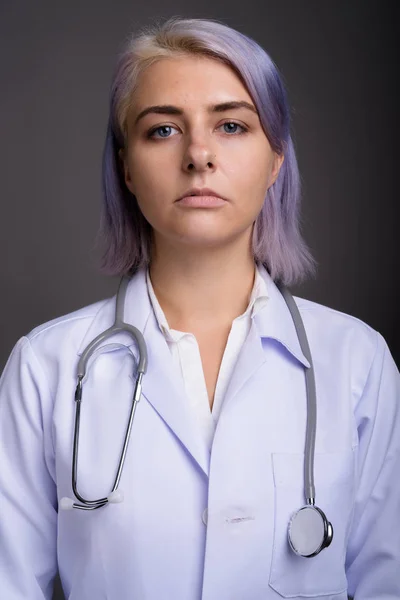 Joven mujer hermosa médico con pelo corto y colorido contra gr —  Fotos de Stock