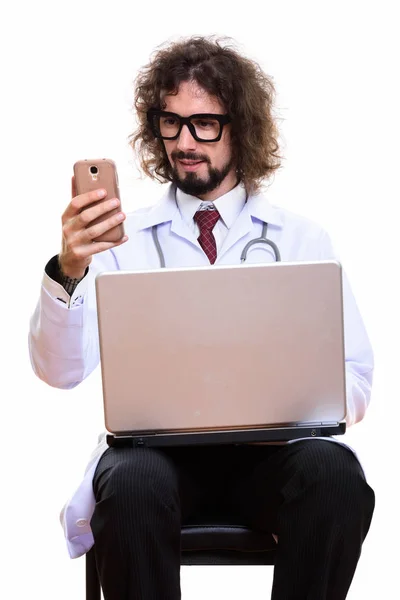 Felice uomo medico sorridente durante l'utilizzo del telefono cellulare con computer portatile — Foto Stock