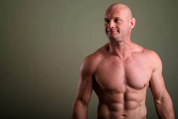 Plešatý svalnatý muž shirtless barevné pozadí — Stock fotografie