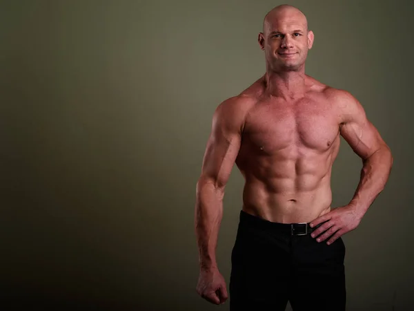 Homem muscular careca sem camisa contra fundo colorido — Fotografia de Stock