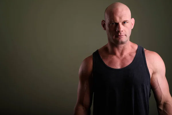 Bald muscular man wearing tank top against colored background
