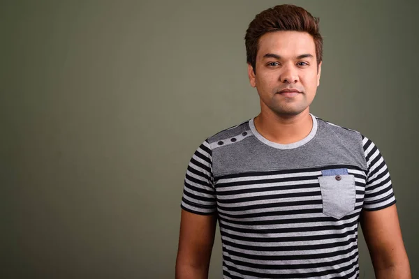 Indian man wearing striped shirt against colored background