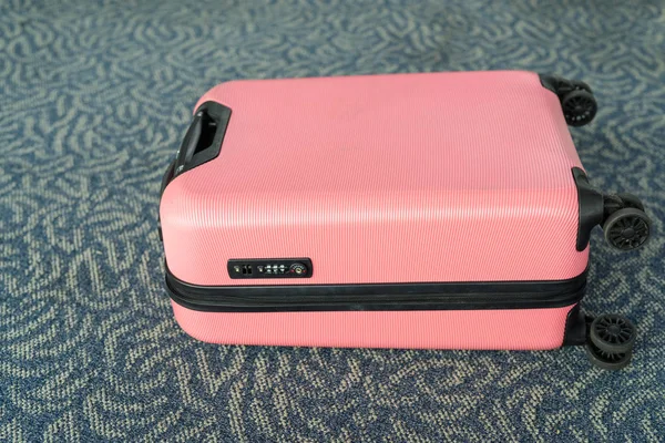 Розовый багаж тележки подходит для легких путешествий, лежащих на ковре — стоковое фото