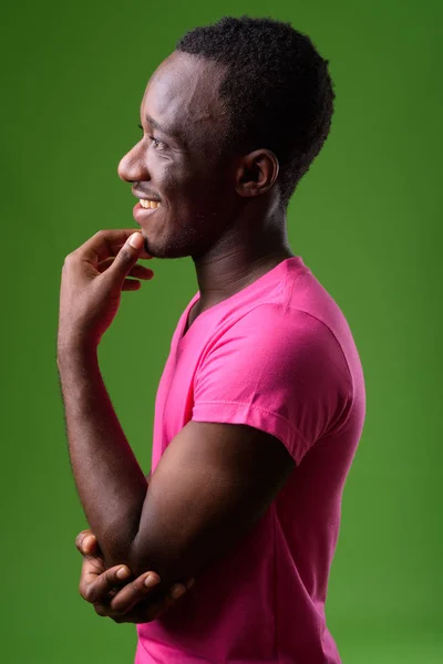 Studio shot of young African man against green background — Stock Photo, Image