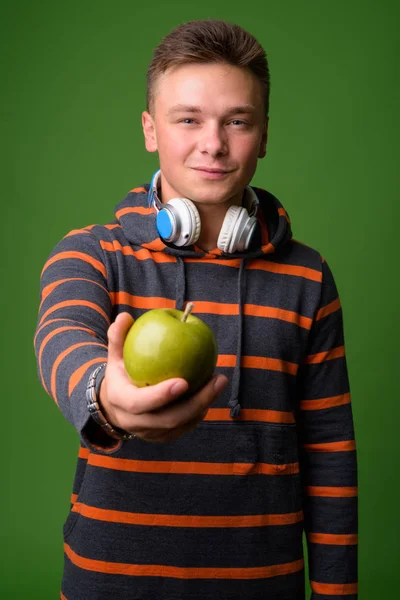 Studio shot of young handsome man against green background — Stock Photo, Image