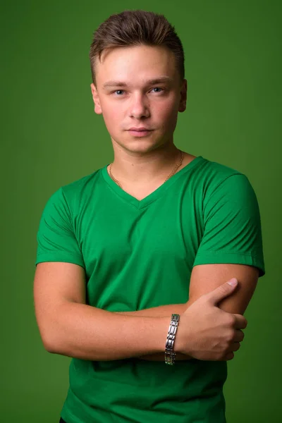 Studio záběr pohledný mladík před zeleným pozadím — Stock fotografie