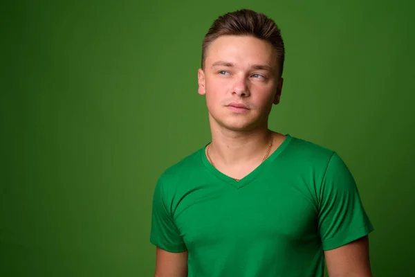 Estúdio tiro de jovem bonito homem contra fundo verde — Fotografia de Stock