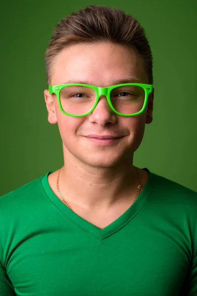 Studio záběr pohledný mladík před zeleným pozadím — Stock fotografie