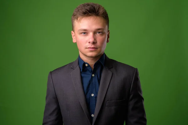 Studio shot of young handsome businessman against green backgrou — Stock Photo, Image