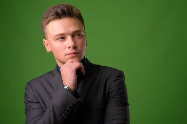 Estudio disparo de joven hombre de negocios guapo contra verde backgrou — Foto de Stock