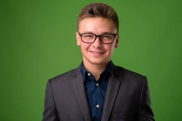 Studio shot of young handsome businessman against green backgrou — Stock Photo, Image