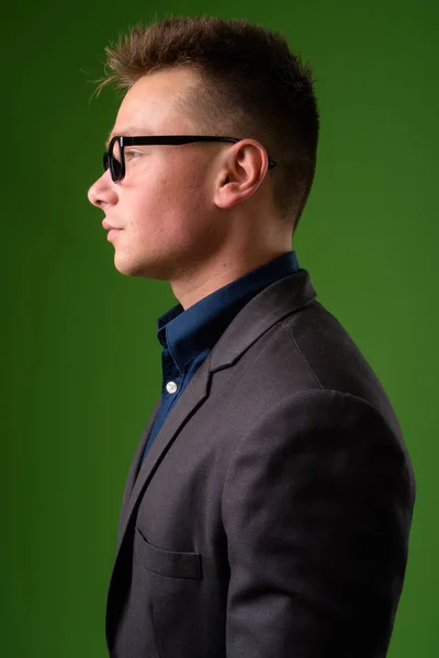 Studio záběr mladá pohledný podnikatel proti zelené poz — Stock fotografie
