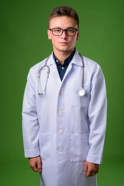 Jovem bonito homem médico contra fundo verde — Fotografia de Stock