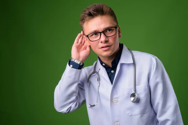 Joven hombre guapo médico contra fondo verde —  Fotos de Stock
