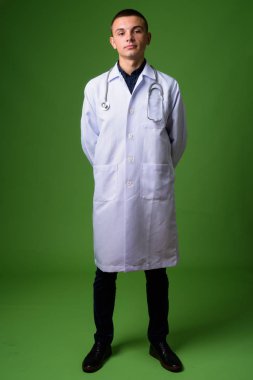 Genç yakışıklı adam doktor yeşil bir arka plana dayanır