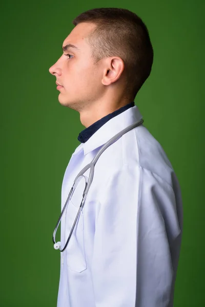 Jovem bonito homem médico contra fundo verde — Fotografia de Stock