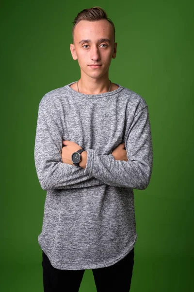 Studio shot of young handsome man against green background — Stock Photo, Image