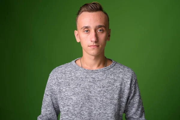 Studio shot of young handsome man against green background — Stock Photo, Image