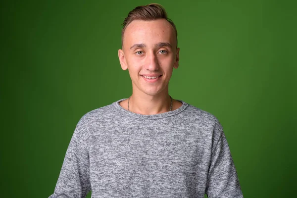 Studio shot of young handsome man against green background — Stock Photo, Image