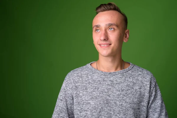 Studio shot of young handsome man against green background — Stock Photo, Image