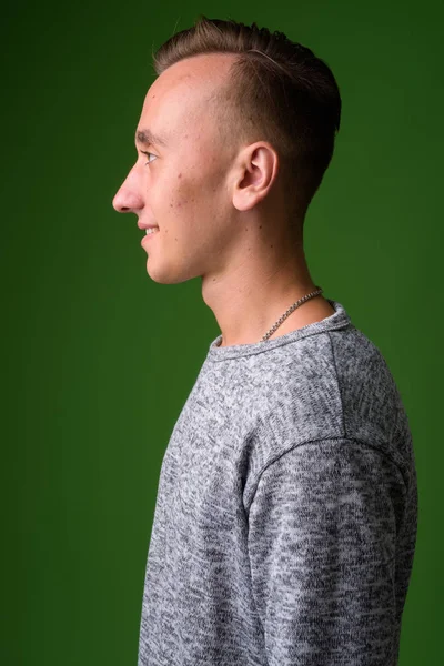 Studio shot of young handsome man against green background — Stock Photo, Image