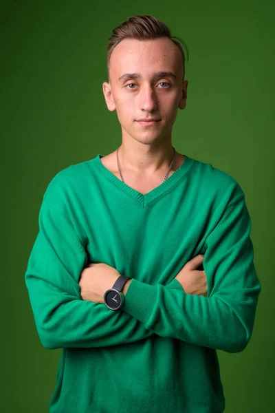 Studio shot of young handsome man against green background — Stock Photo, Image