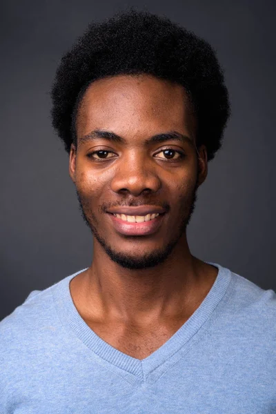 Genç yakışıklı Afrikalı adamın gri arka plan yüzü — Stok fotoğraf